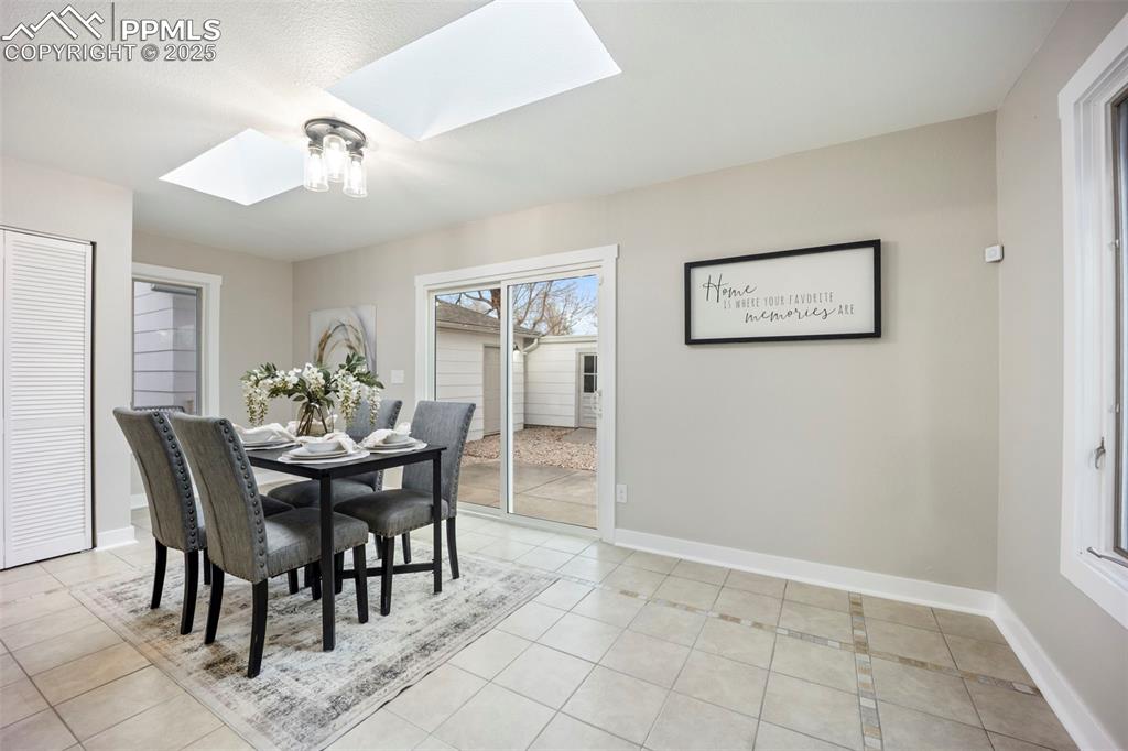 Dining area with a skylight and light tile patterned floors
