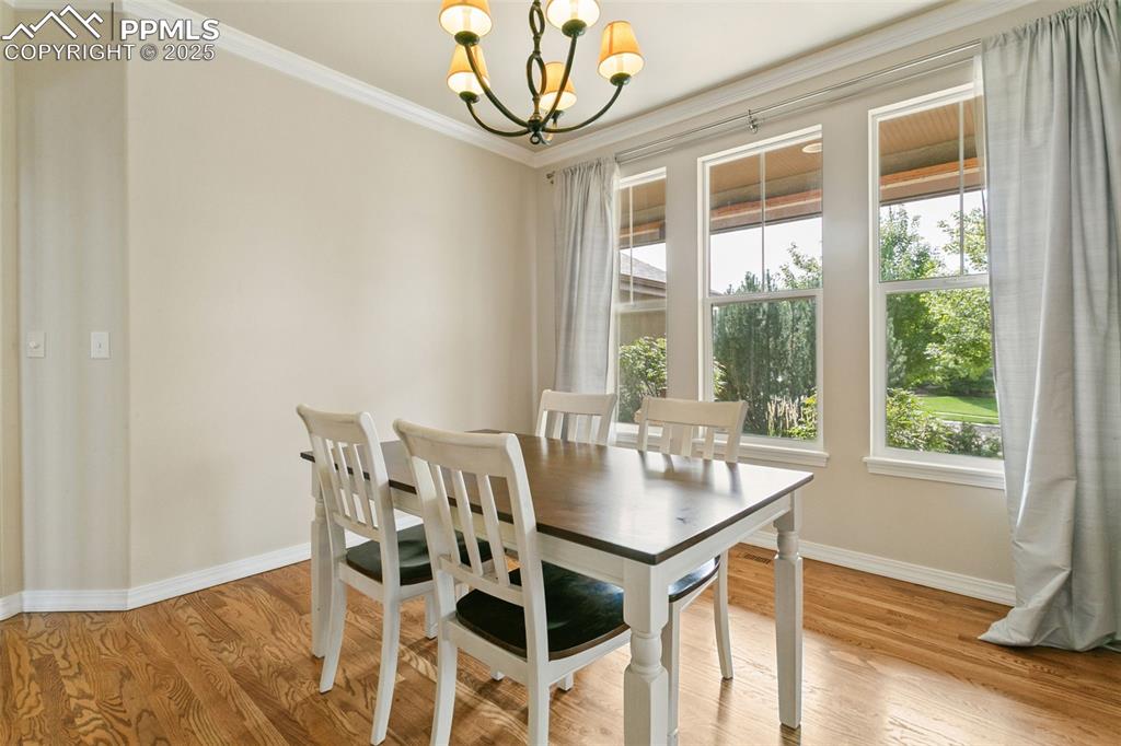 Dining area with ornamental molding, a chandelier, and light wood-style flooring