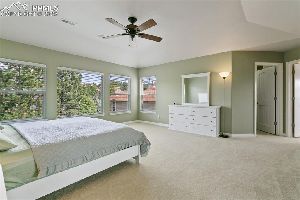 Bedroom featuring light colored carpet, vaulted ceiling, and a ceiling fan