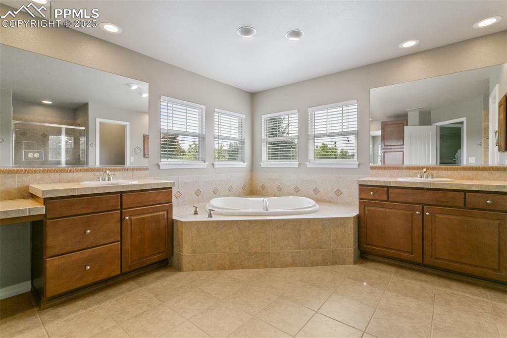 Bathroom with a shower stall, two vanities, light tile patterned floors, a bath, and recessed lighting