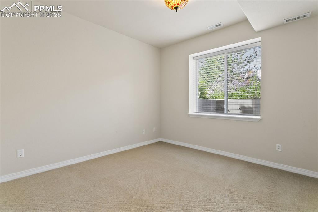 Unfurnished room featuring light carpet and baseboards