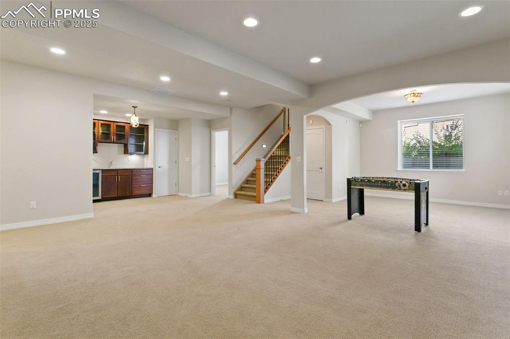 Rec room featuring recessed lighting, light carpet, arched walkways, wet bar, and beverage cooler