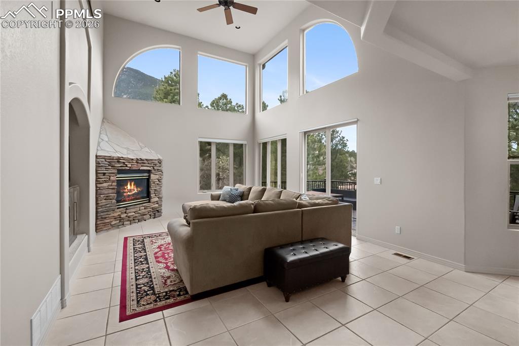 Living room with vaulted ceilings, fireplace, mountain views, and mature trees.