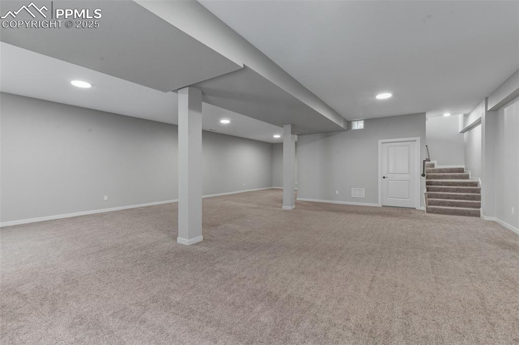 Finished below grade area featuring light carpet, stairs, and recessed lighting