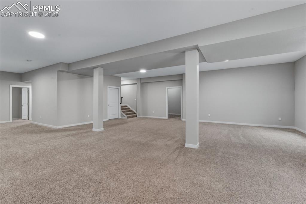 Finished below grade area featuring light carpet, stairs, and recessed lighting