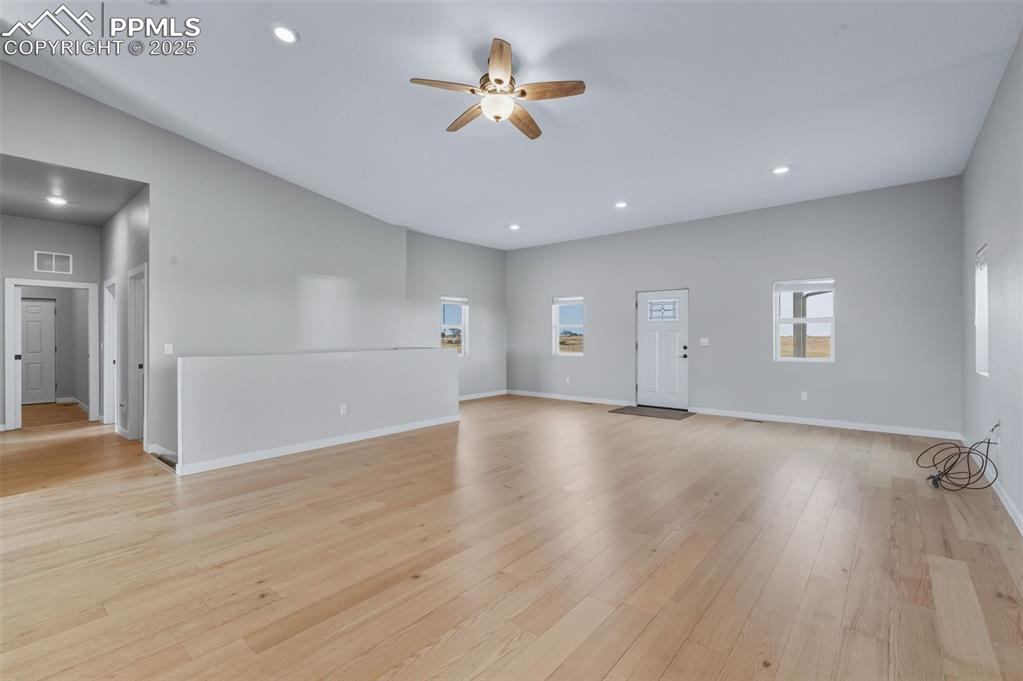 Unfurnished living room featuring a ceiling fan, light wood-type flooring, and recessed lighting