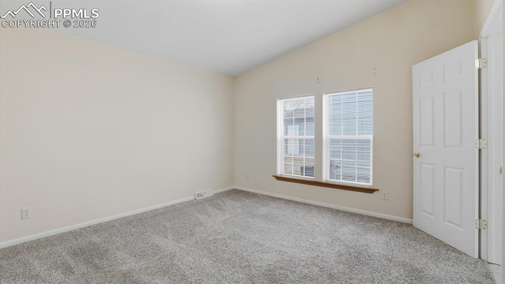 The vaulted Primary Bedroom offers neutral carpet and a large view window.