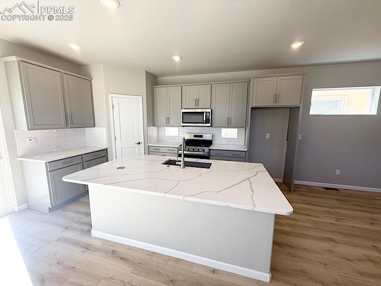 Kitchen with Quartz slab countertops, pantry, large island providing additional seating, single bowl composite sink, gas range, microwave, and dishwasher! The chef will enjoy prepping meals in this Kitchen!