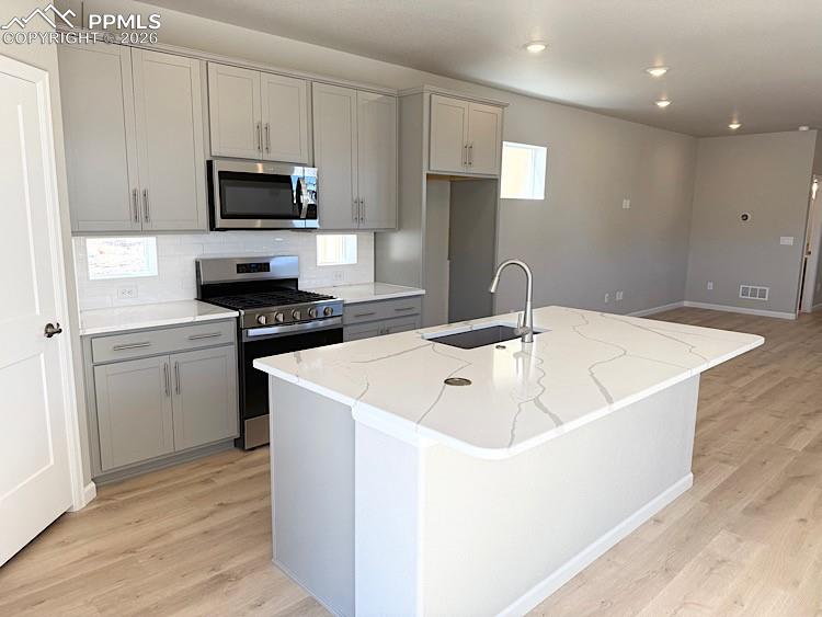 Kitchen with Quartz slab countertops, pantry, large island providing additional seating, single bowl composite sink, gas range, microwave, and dishwasher! The chef will enjoy prepping meals in this Kitchen!
