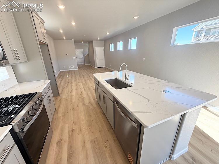 Kitchen with Quartz slab countertops, pantry, large island providing additional seating, single bowl composite sink, gas range, microwave, and dishwasher! The chef will enjoy prepping meals in this Kitchen!