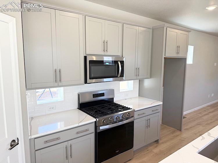 Kitchen with Quartz slab countertops, pantry, large island providing additional seating, single bowl composite sink, gas range, microwave, and dishwasher! The chef will enjoy prepping meals in this Kitchen!