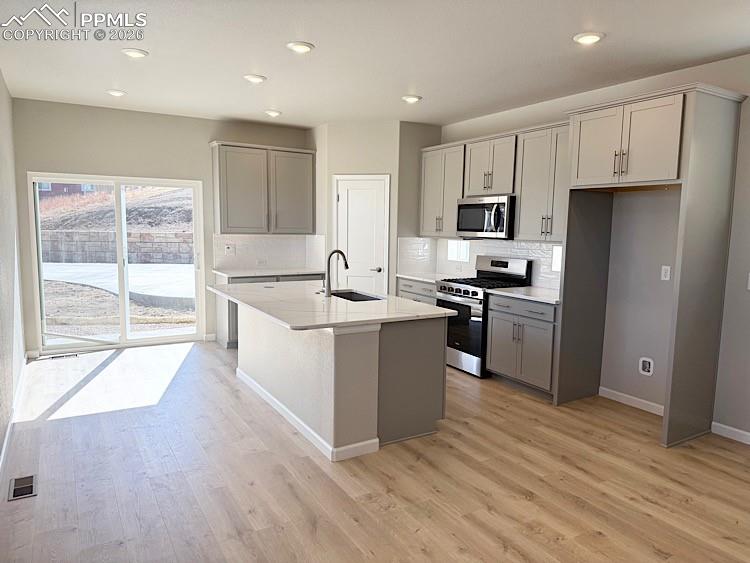 Kitchen with Quartz slab countertops, pantry, large island providing additional seating, single bowl composite sink, gas range, microwave, and dishwasher! The chef will enjoy prepping meals in this Kitchen!