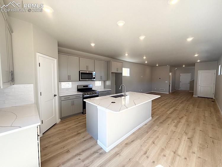 Kitchen with Quartz slab countertops, pantry, large island providing additional seating, single bowl composite sink, gas range, microwave, and dishwasher! The chef will enjoy prepping meals in this Kitchen!