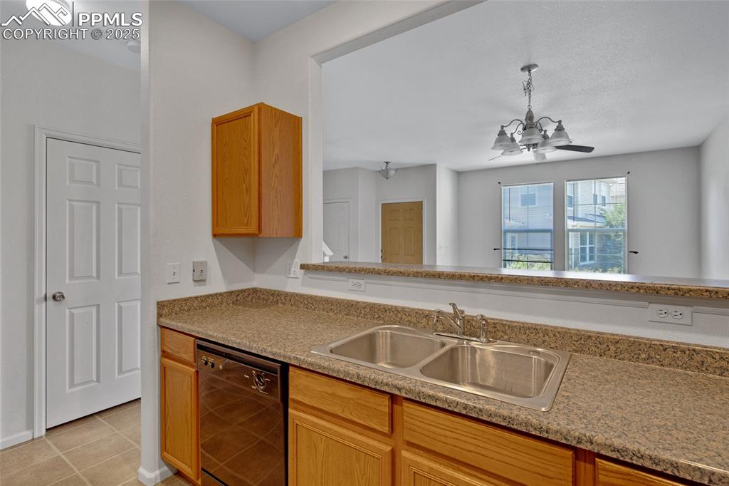 Kitchen featuring dishwasher, light tile patterned flooring, a chandelier, pendant lighting, and light countertops