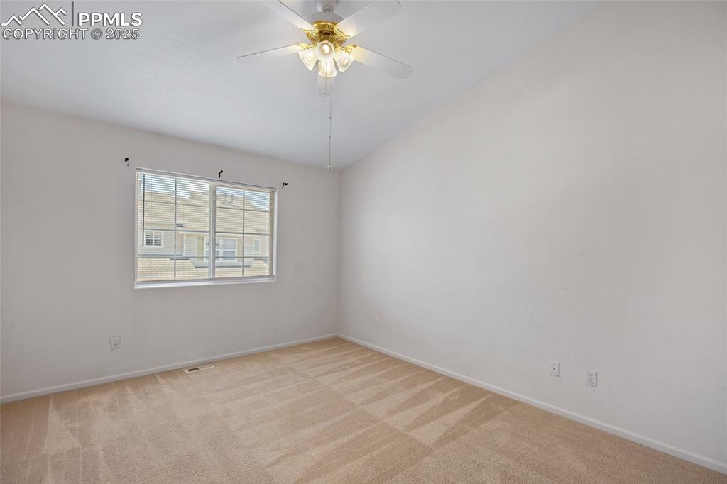 Empty room featuring light carpet and a ceiling fan