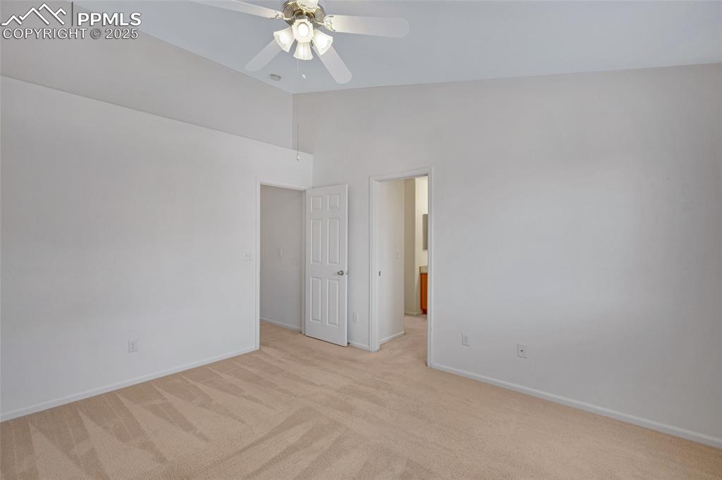 Empty room featuring light colored carpet, a ceiling fan, and high vaulted ceiling