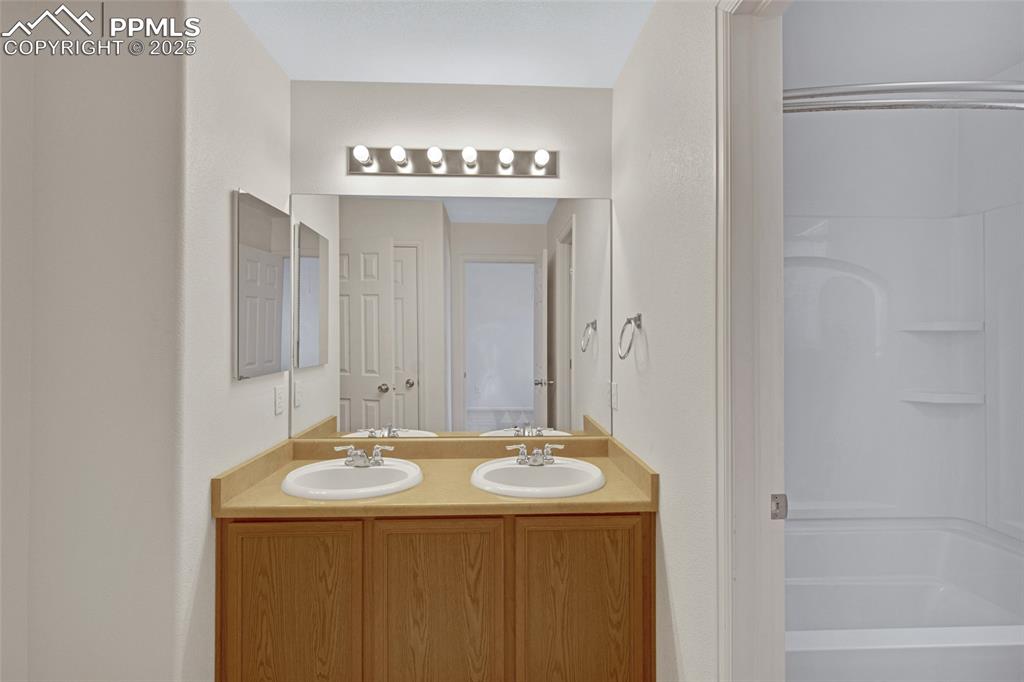 Bathroom featuring double vanity and bathing tub / shower combination