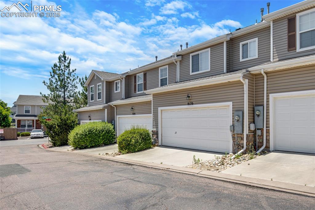 View of property with driveway, a garage, and stone siding