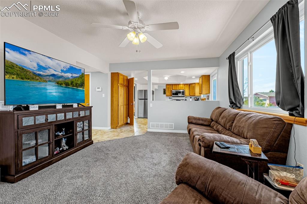 Living area featuring a ceiling fan, light carpet, and recessed lighting