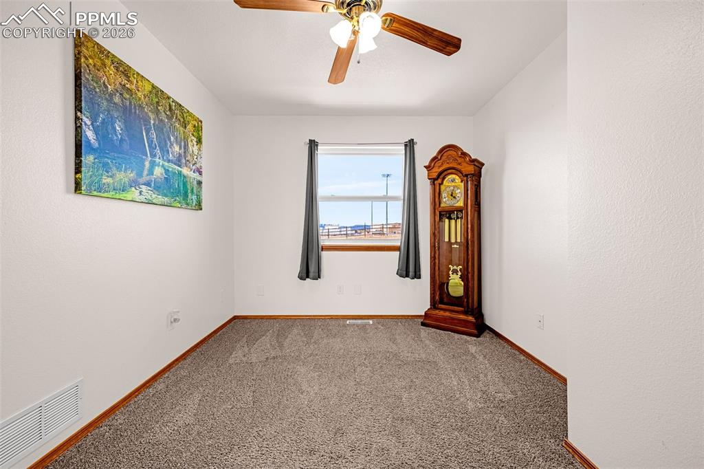 Carpeted empty room with a ceiling fan and a textured wall
