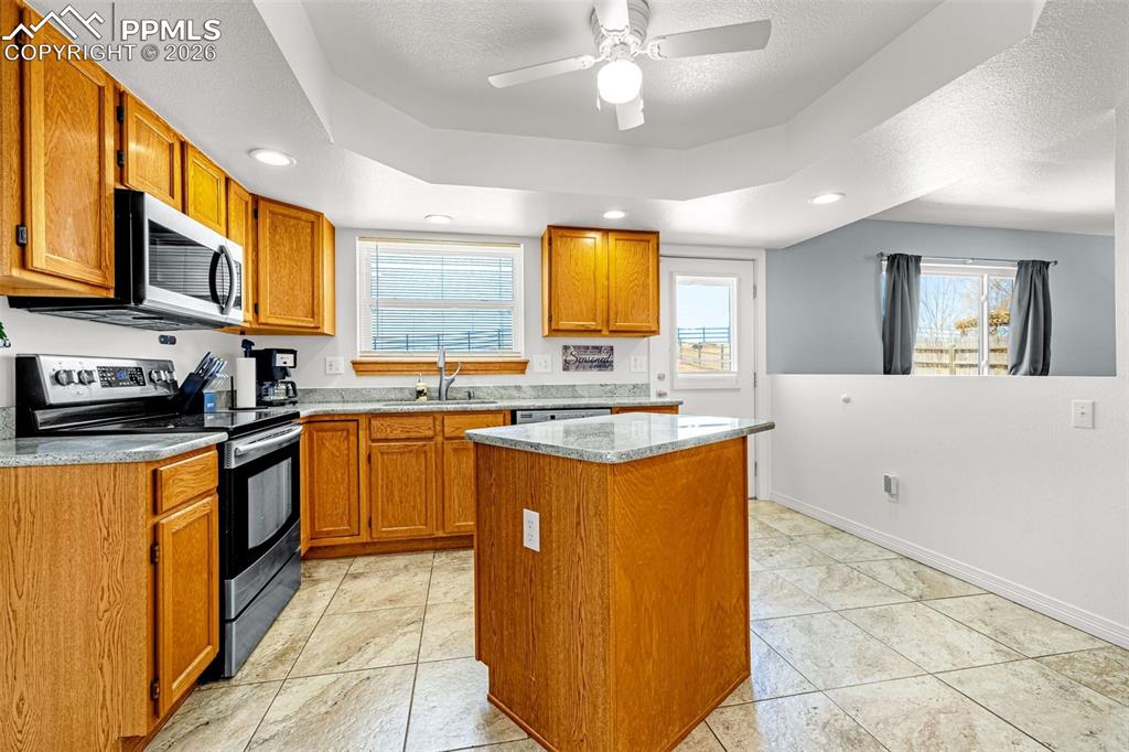 Kitchen featuring stainless steel appliances, a center island, a ceiling fan, recessed lighting, and wood finish cabinets