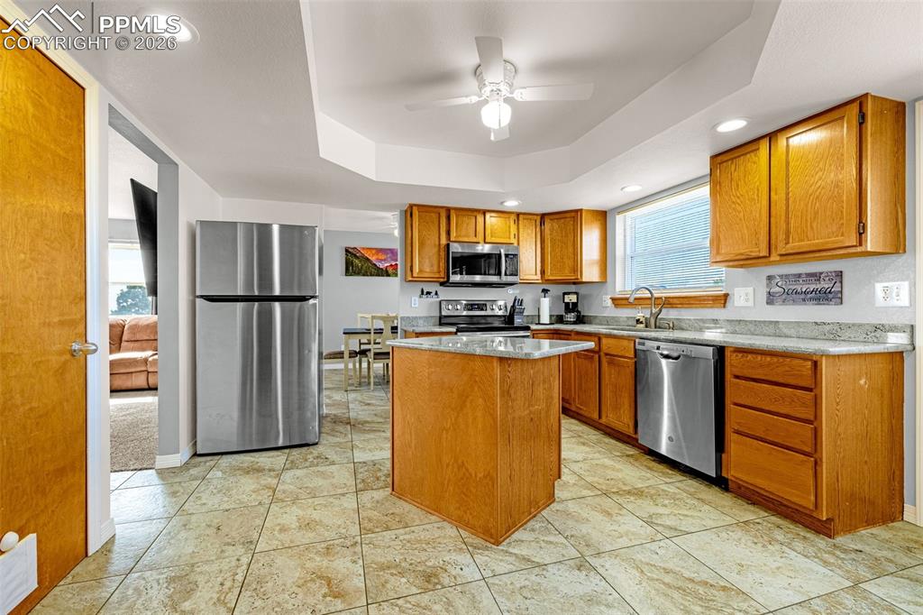 Kitchen featuring stainless steel appliances, light stone counters, recessed lighting, a ceiling fan, and wood finish cabinets