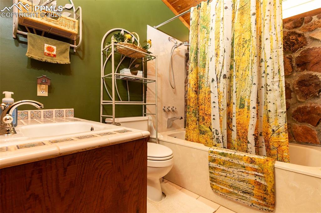Full bath featuring shower / bath combination with curtain, vanity, and tile patterned flooring