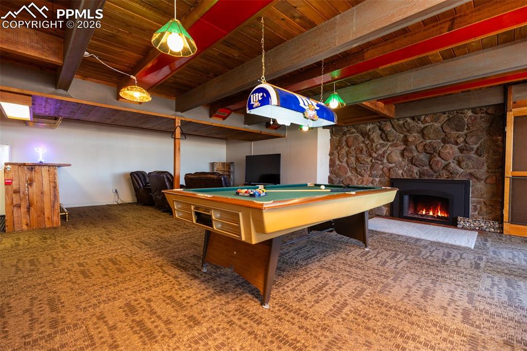 Game room featuring billiards, a fireplace, and a wood ceiling with exposed beams