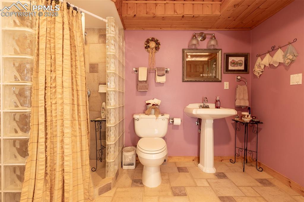 Full bathroom with wooden ceiling, a stall shower, and stone finish floors