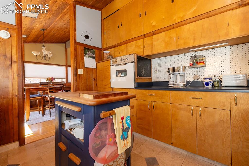 Kitchen with open shelves, white oven, butcher block counters, a chandelier, and light tile patterned floors