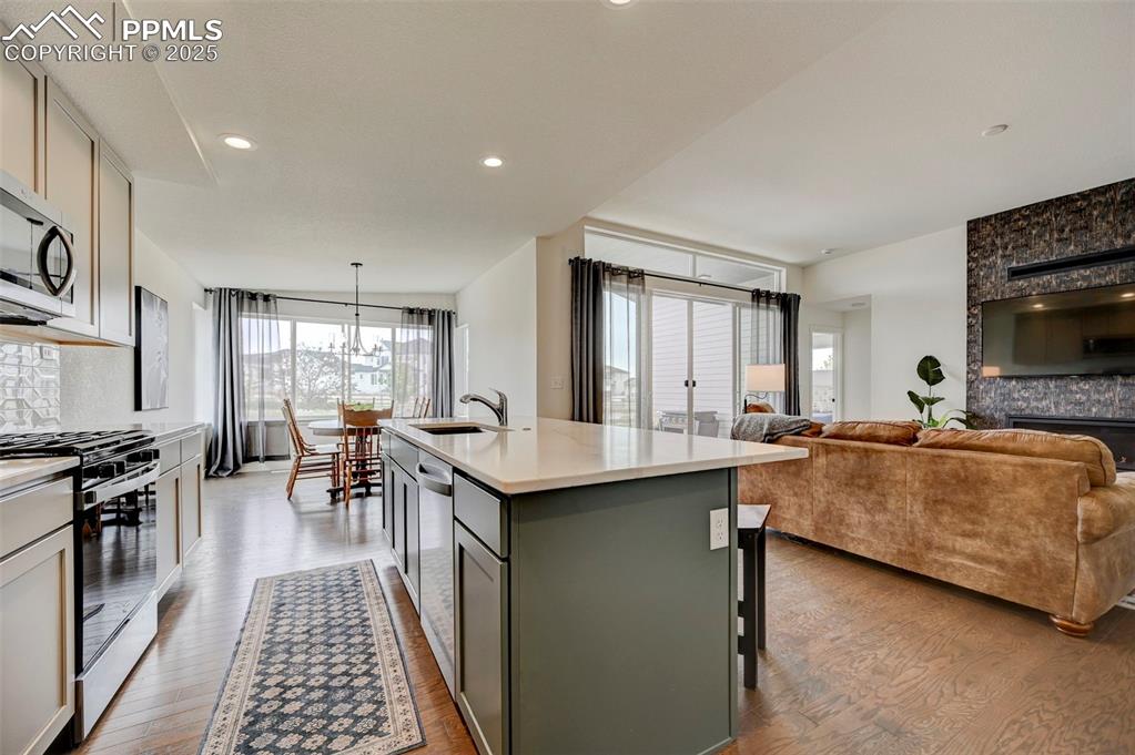 Kitchen with stainless steel appliances, a sink, wood finished floors, gray cabinets, and light countertops