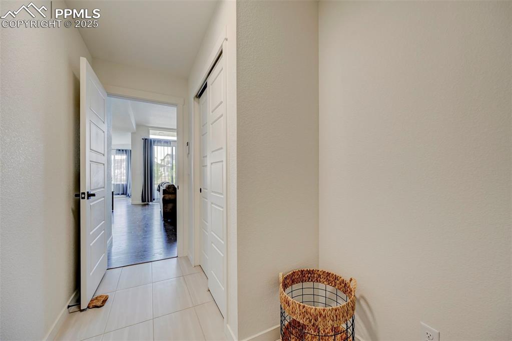 Hall with light tile patterned flooring and baseboards