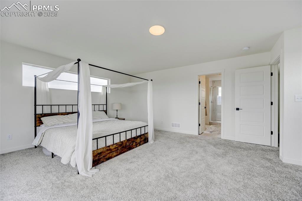 Bedroom with carpet floors, baseboards, and connected bathroom