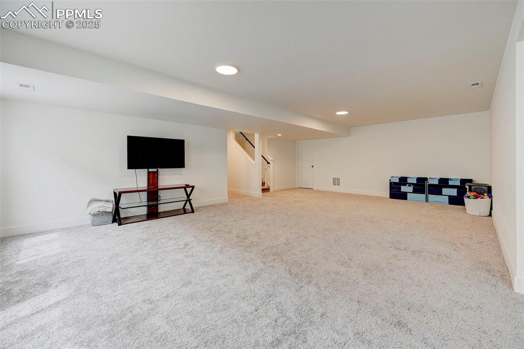 Finished below grade area featuring baseboards, carpet flooring, stairway, and recessed lighting