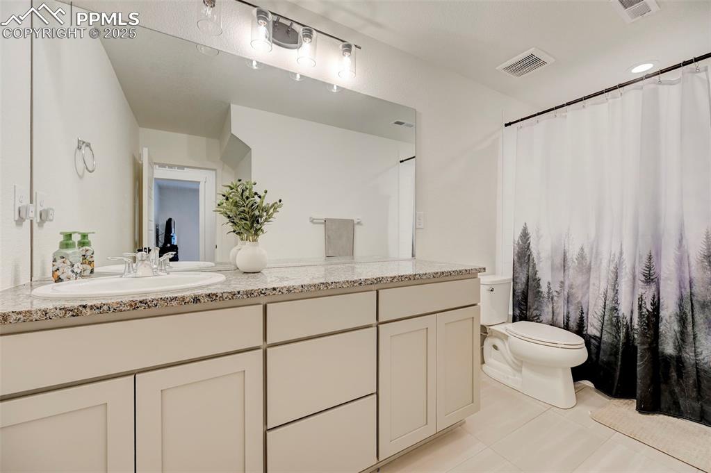 Bathroom with toilet, vanity, and tile patterned flooring