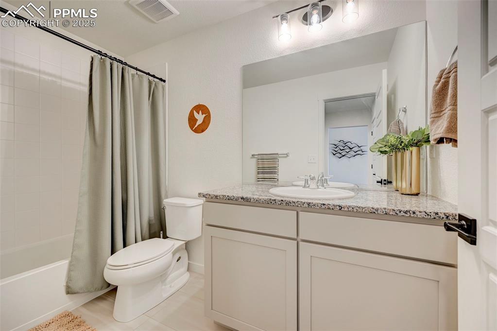 Bathroom with toilet, vanity, tile patterned floors, and shower / tub combo with curtain
