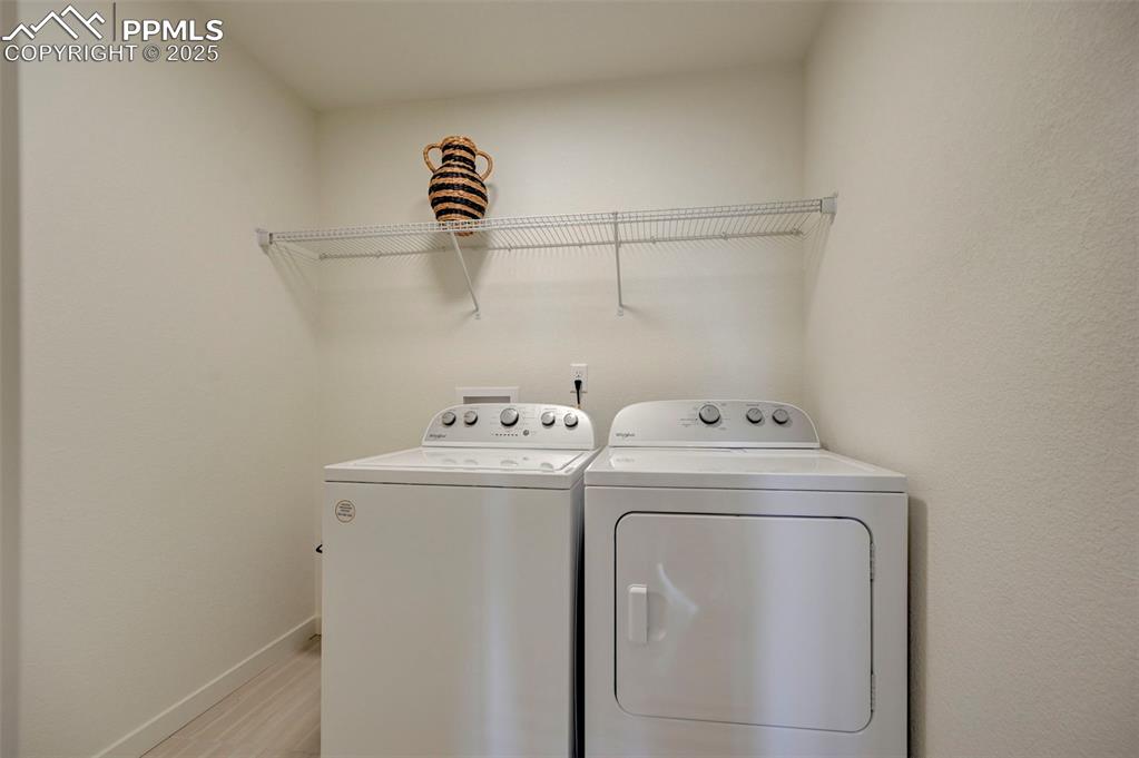 Laundry area with washer and clothes dryer, light wood-style flooring, and baseboards