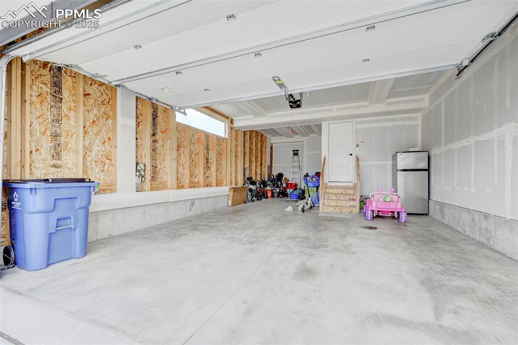 Garage with freestanding refrigerator and a garage door opener