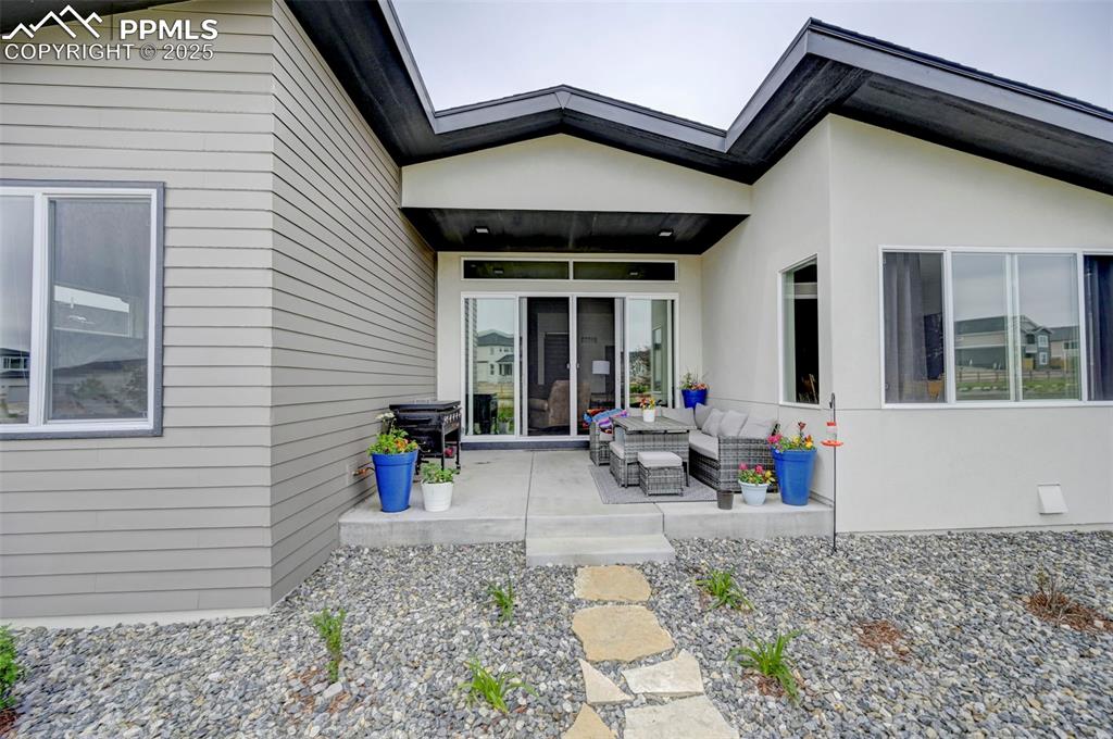 Entrance to property with an outdoor living space, a patio area, and stucco siding