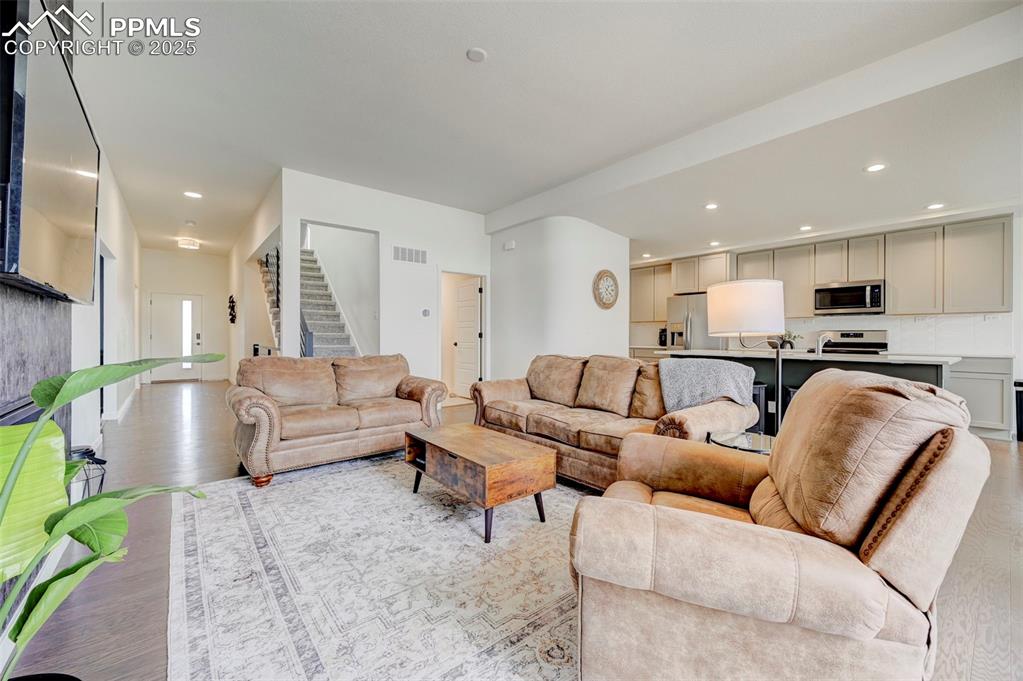 Living area with stairs, light wood-style flooring, and recessed lighting