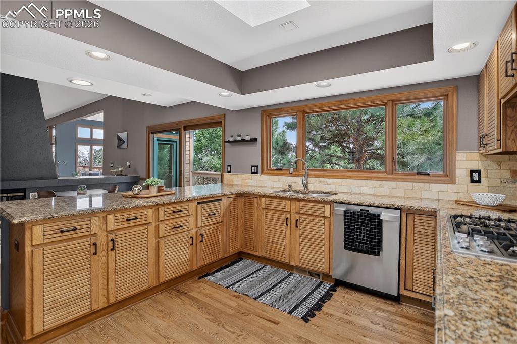 Kitchen with a peninsula, a skylight, recessed lighting, light wood-type flooring, and stainless steel appliances