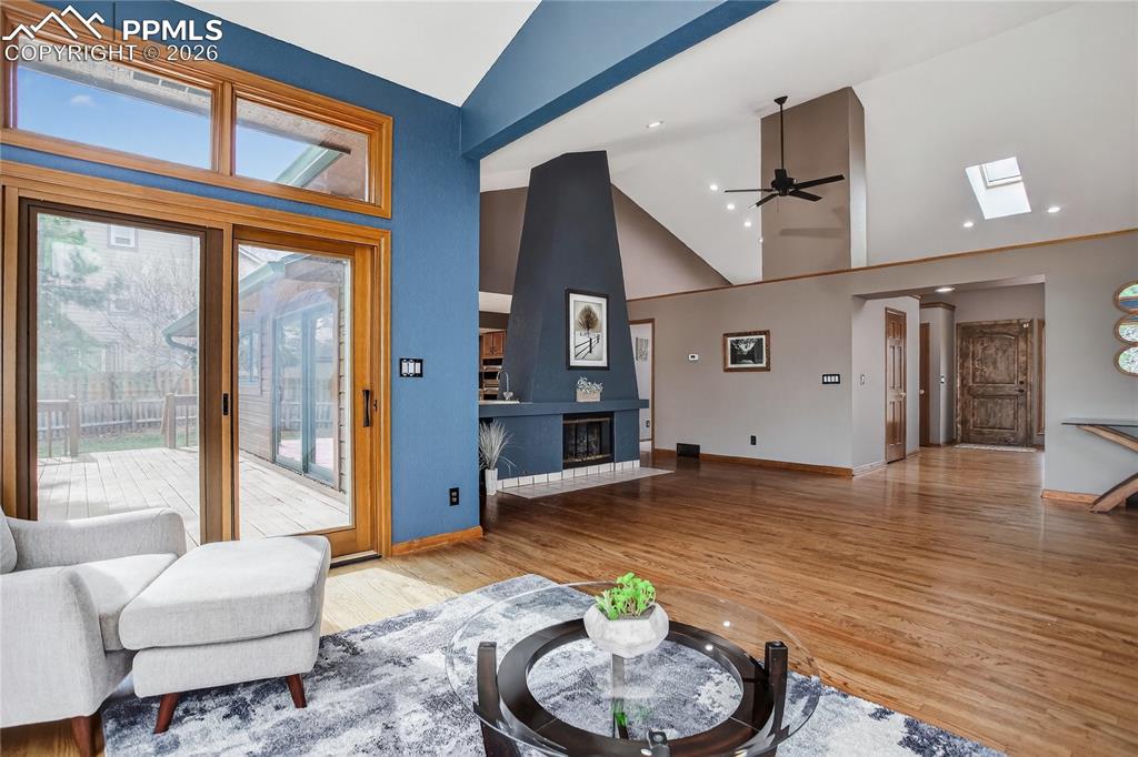 Living area with ceiling fan, track lighting, wood finished floors, and high vaulted ceiling