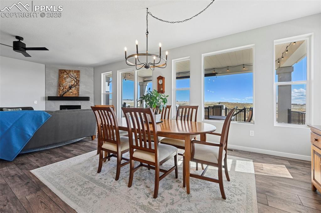 Dining area featuring a fireplace, dark wood-style flooring, a chandelier, and a ceiling fan