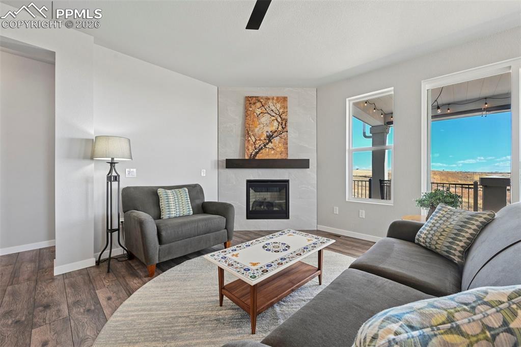 Living room featuring wood finished floors, a fireplace, and a ceiling fan