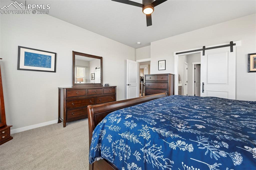 Primary Bedroom Carpeted with a barn door and ceiling fan
