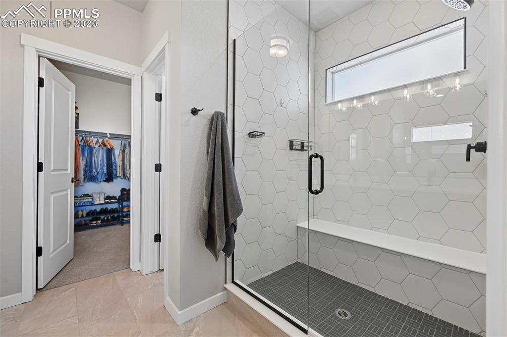 Primary bath featuring a spacious closet and a shower stall