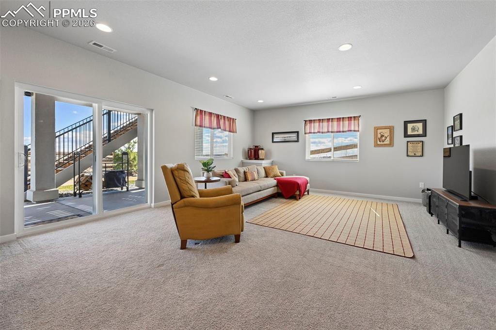 Basement family room with light colored carpet and recessed lighting
