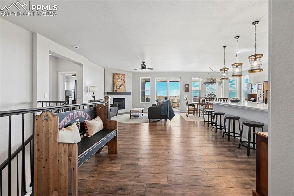 Living room featuring dark wood-style flooring, a glass covered fireplace, and ceiling fan