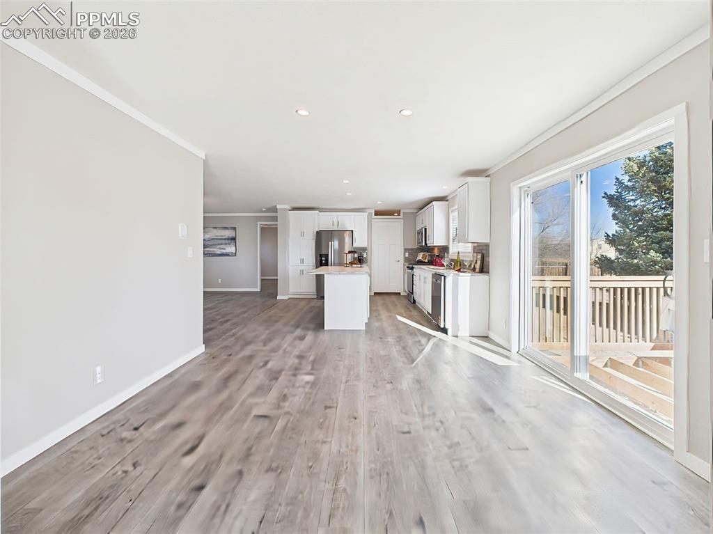 Kitchen & Family Room View – The heart of the home features a bright kitchen with white shaker cabinets, a center island, stainless steel appliances, and open sightlines to the spacious family room.