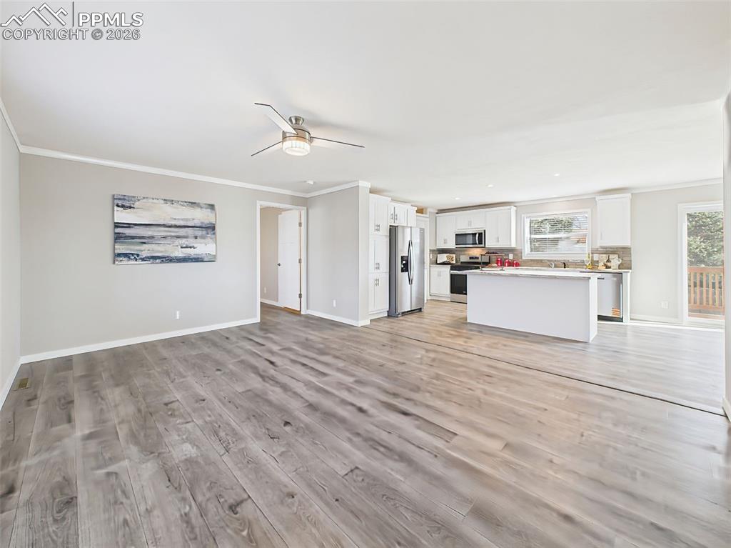 Family Room with Kitchen View (Unstaged) – Clean lines and open flow continue with ample natural light and views into the bright white kitchen with island seating.